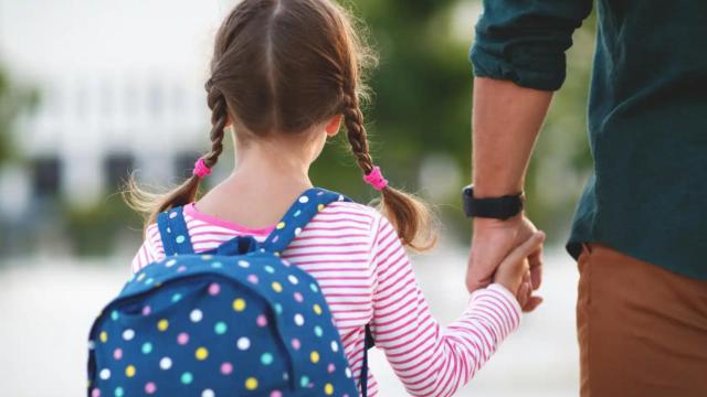 Una niña va al colegio con su padre.