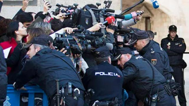 Un grupo de periodistas contenido por un retén policial.