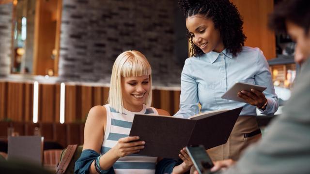 Camarera tomando pedido a clienta.