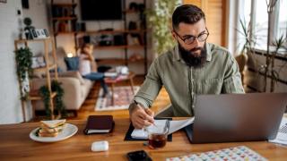 Padre trabajando desde casa; de fondo, su hija.