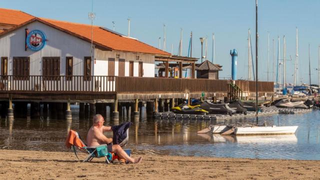 Un hombre toma el sol en la playa en pleno invierno.