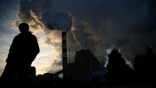 Un hombre camina mientras el humo y el vapor salen de la central eléctrica de Belchatow, la mayor central eléctrica de lignito de Europa.