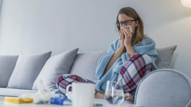 Imagen de una mujer resfriada en su sofá.