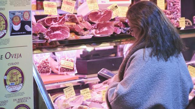 Una mujer paga en una carnicería.