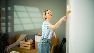 Mujer pintando la pared de su casa.