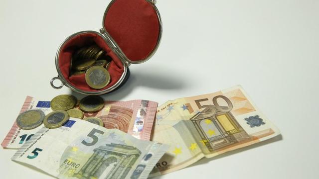 Imagen de archivo de varios billetes y monedas en un monedero.