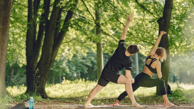 Imagen de una pareja realizando yoga al aire libre.