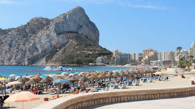 Turistas en la playa de Calpe con el peñón de Ifach al fondo.