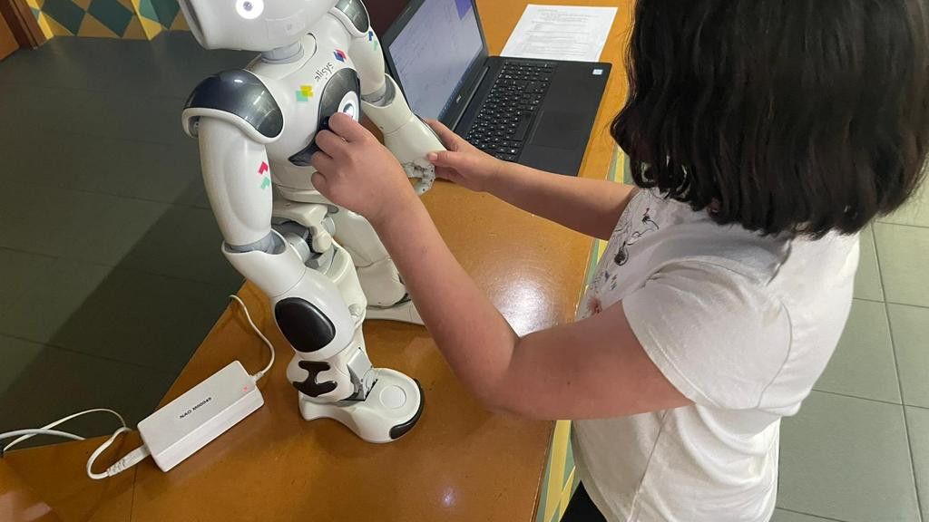 Una niña juega con Nao, el robot asistente.