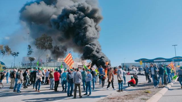 Unos agricultores cortan el acceso al Puerto de Castellón con una barricada de neumáticos.