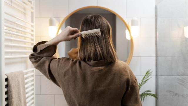 Mujer de espaldas peinándose.