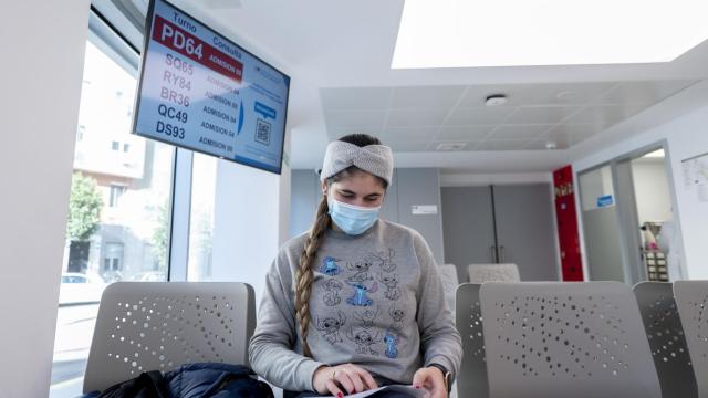 Una paciente aguada en la sala de espera del médico con la mascarilla puesta.