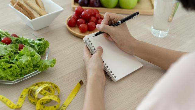 Persona escribiendo propósitos de alimentación.