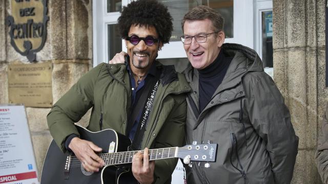 El líder del Partido Popular, Alberto Núñez Feijóo, bromea con un músico callejero.