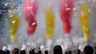 Varias personas observan el humo de colores durante la primera mascletà madrileña, en el Puente del Rey de Madrid.