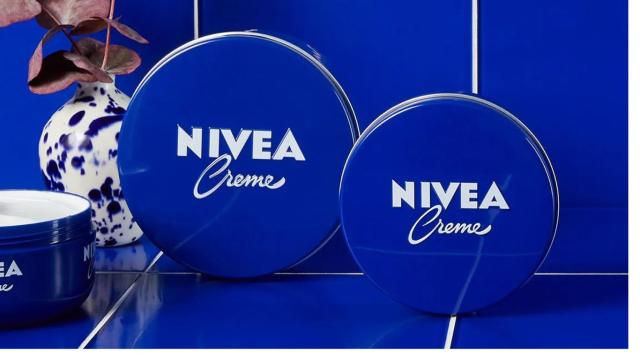 Latas de crema Nivea sobre fondo azul.