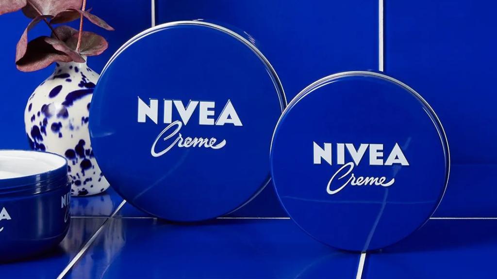 Latas de crema Nivea sobre fondo azul.