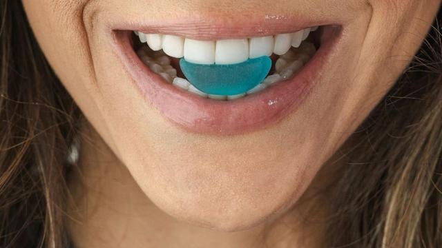 Una mujer tomando un tratamiento en forma de gominola.