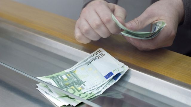 Persona contando dinero en una ventanilla