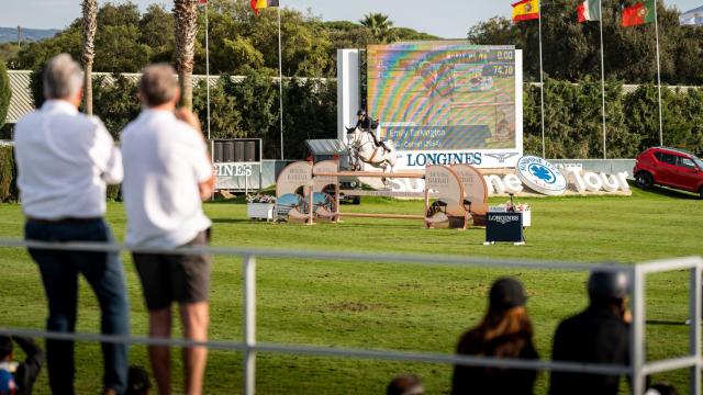 Dos asistentes observan el desempeño de un caballo de competición.