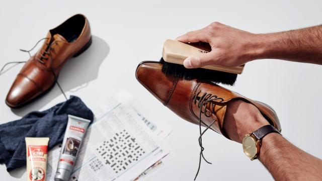 Hombre limpiando zapatos con un cepillo.