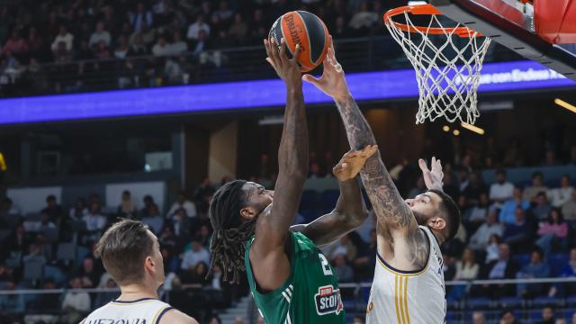 El ala-pívot francés del Panathinaikos Mathias Lessort (c) entra a canasta ante el pívot francés del Real Madrid Vincent Poirier.