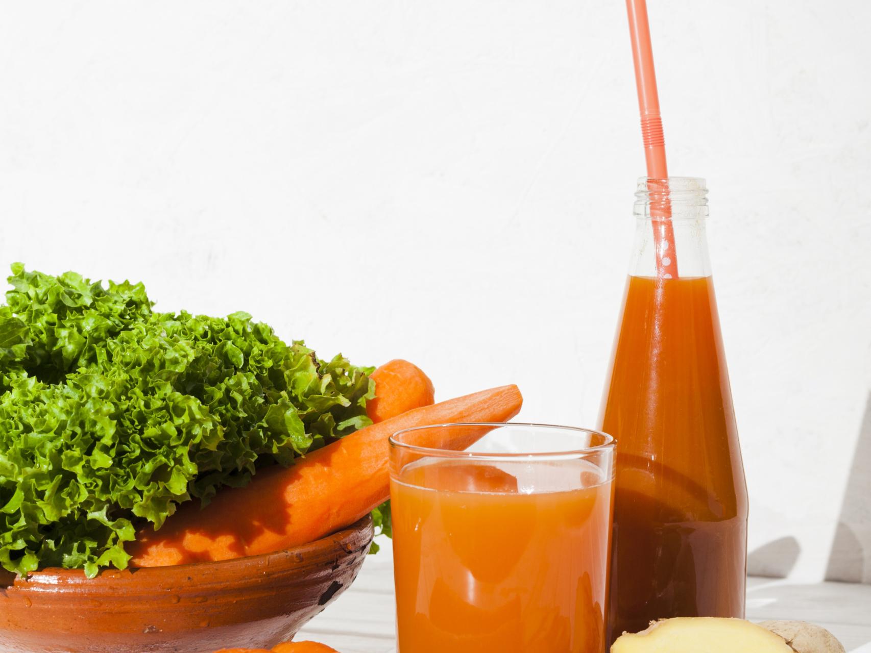 Mesa con ingredientes para hacer un zumo de zanahoria.