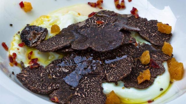 Un plato de huevos acompañados con trufa negra
