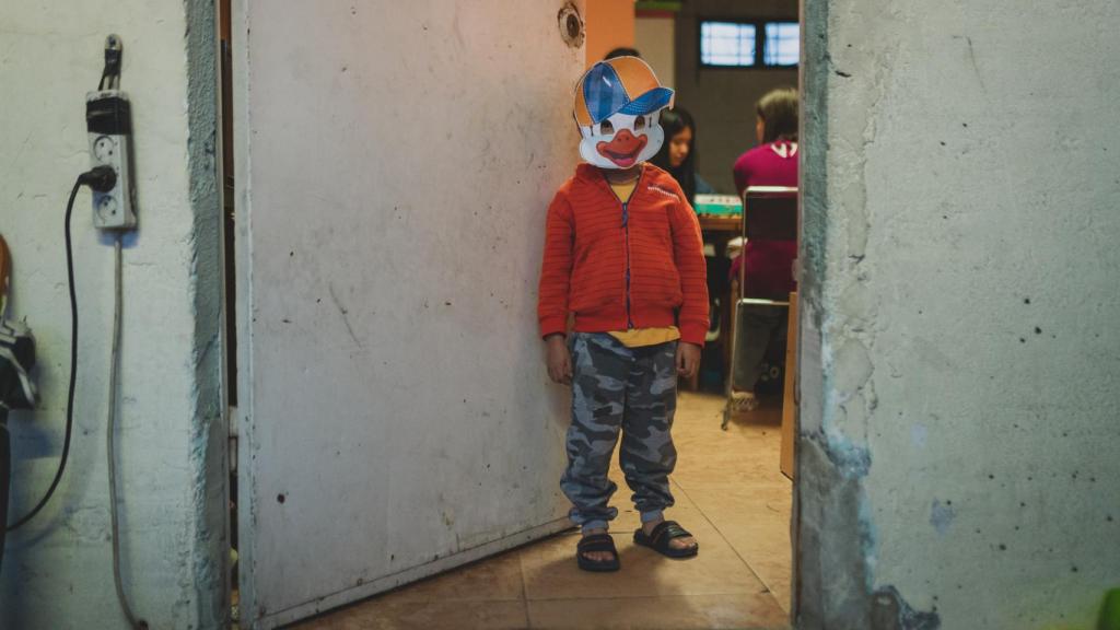 Cristóbal juega con una careta en la puerta de su casa.