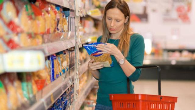 Una mujer mirando un producto mientras hace la compra