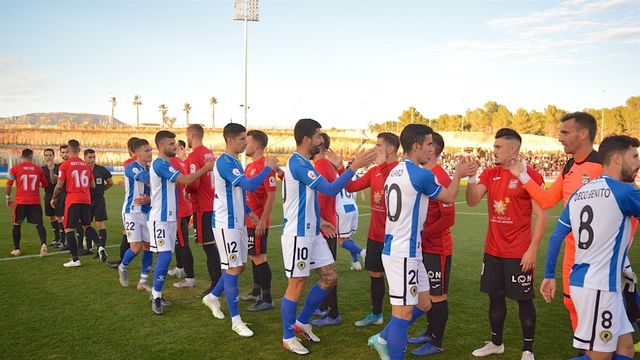Los jugadores del hércules saludan a los de La Nucía en los prolegómenos de un partido.