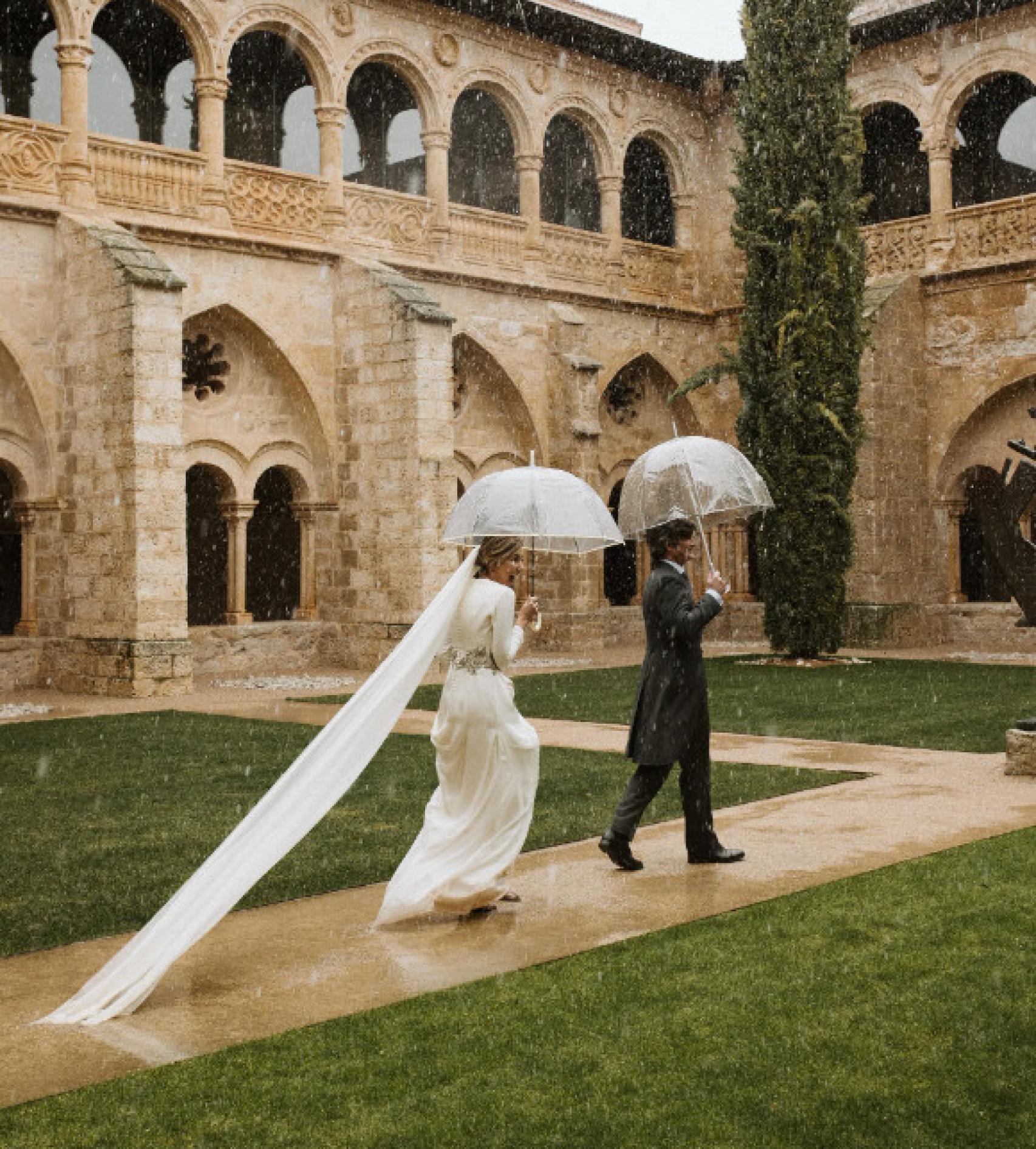 Los novios caminando con el paraguas bajo el temporal