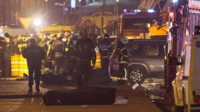 Los especialistas se reúnen cerca de los cuerpos cubiertos de personas asesinadas cerca de la sala de conciertos Crocus City Hall.