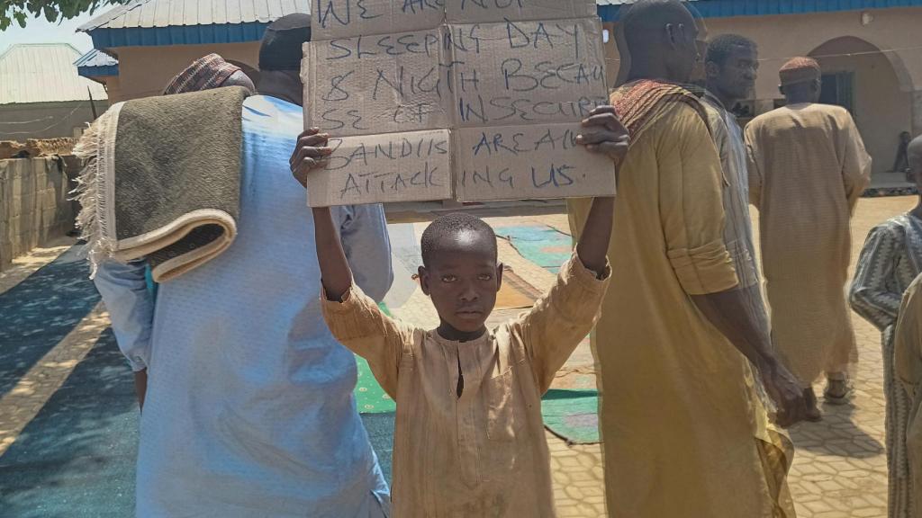Un niño sostiene un cartel para protestar contra lo que dijeron un maestro, un concejal local y sus padres: el secuestro de cientos de alumnos por hombres armados después de la oración del viernes en Kaduna, Nigeria.