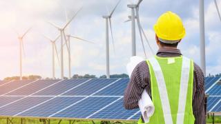 Un trabajador mira un parque eólico y uno fotovoltaico.