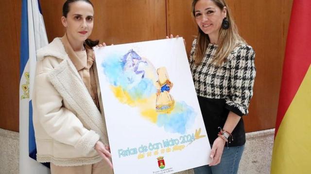 La autora de la obra (i) y la concejal de Festejos (d) posan con el cartel anunciador.