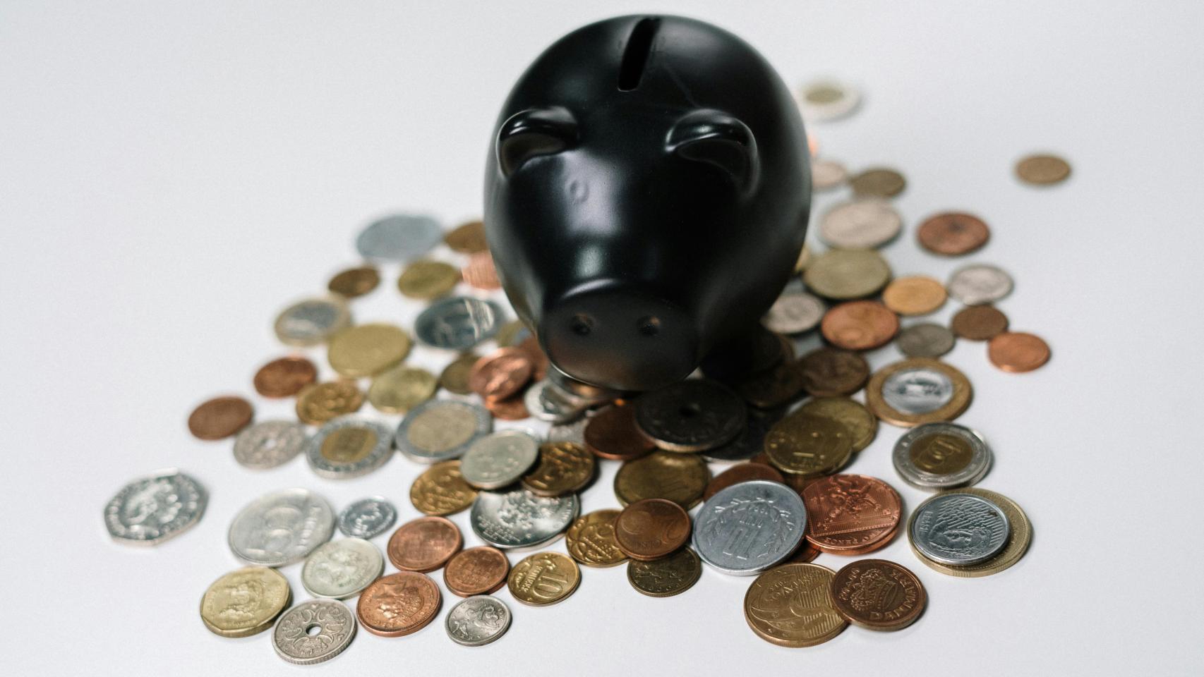 Una hucha con monedas alrededor.