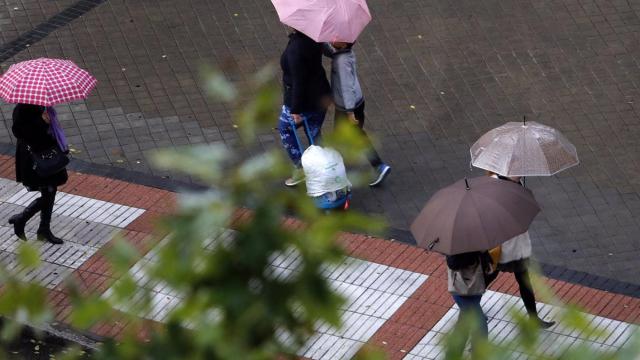 Imagen de archivo de varias personas protegiéndose de la lluvia.