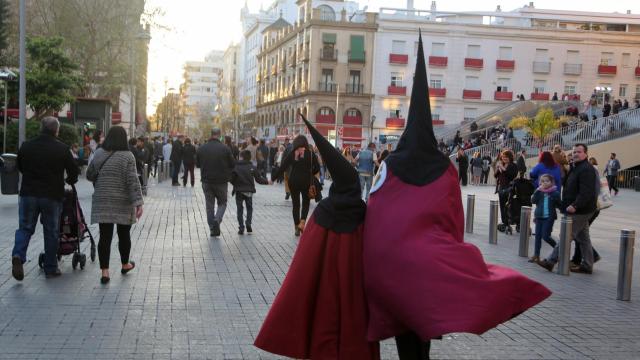 Nazarenos y públicos por el Centro de Sevilla.