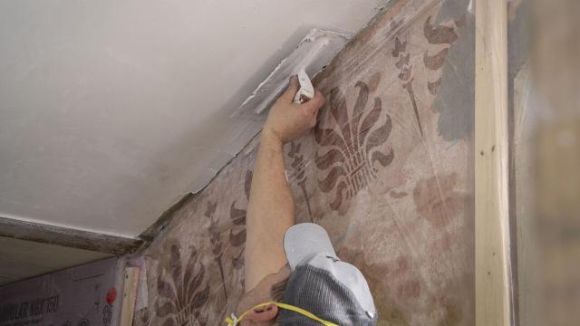 Una persona poniendo yeso en un techo.