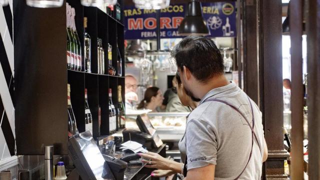 Dos camareros cobran las cuentas de los clientes.