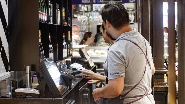 Dos camareros cobran las cuentas de los clientes.