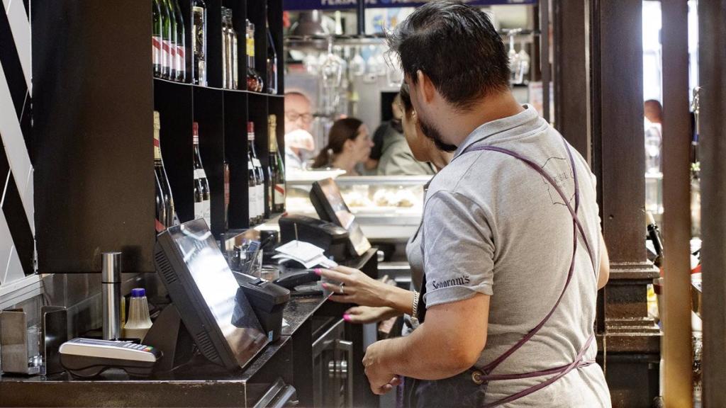 Dos camareros cobran las cuentas de los clientes.