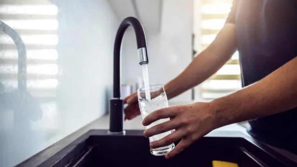 Una persona llena un vaso con agua del grifo.