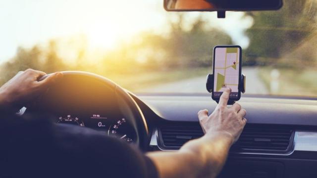 Una persona manipulando su teléfono móvil dentro del coche