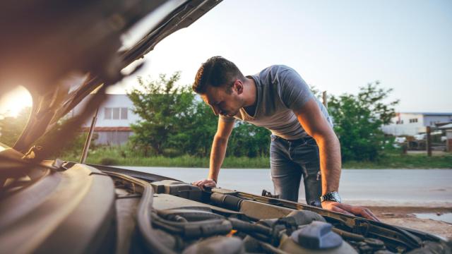 Imagen de un hombre mirando debajo del capó del coche