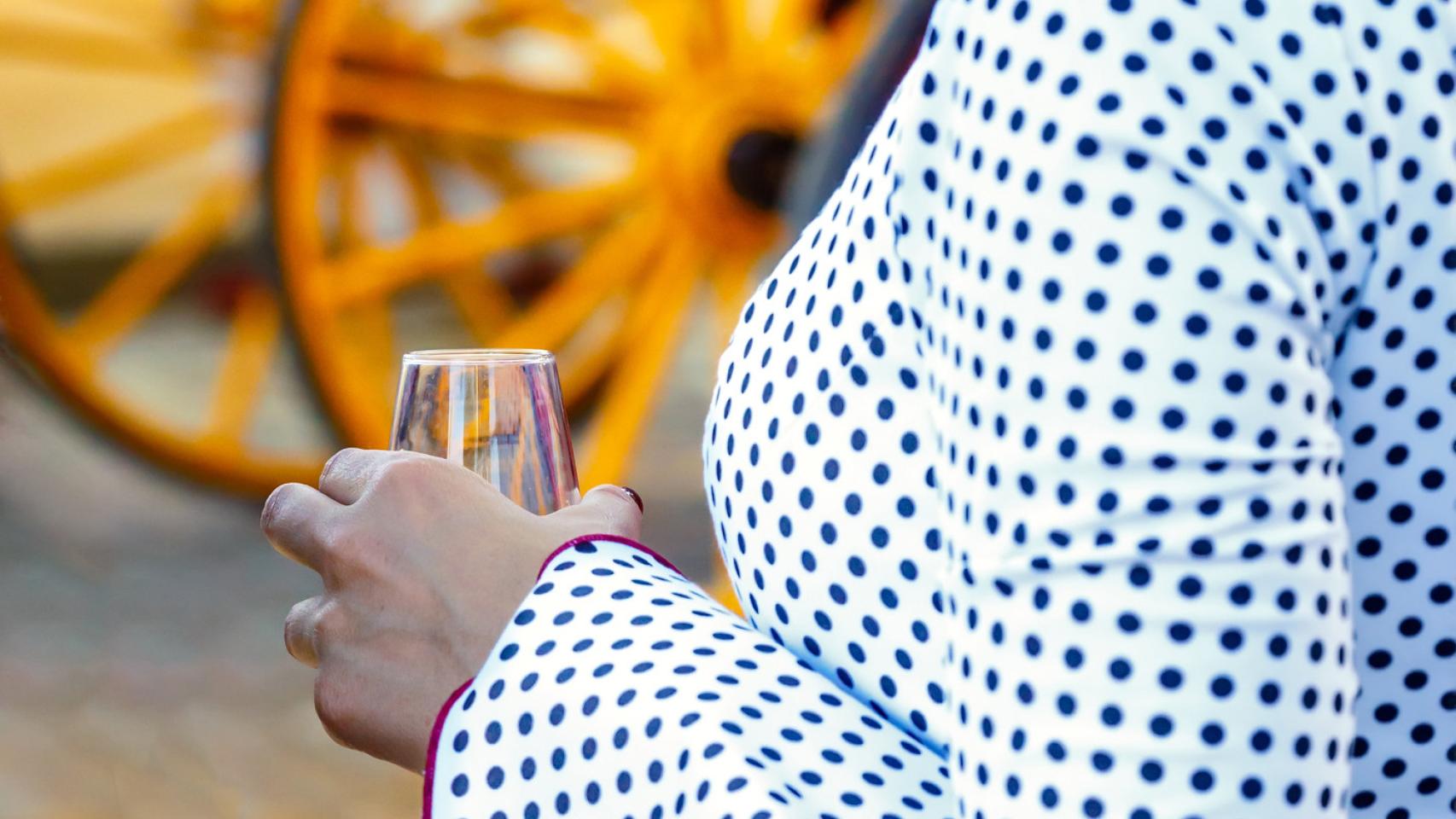 Imagen de una mujer vestida de flamenca con una copa de vino