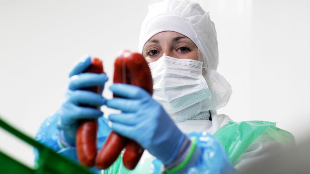 Una empleada trabaja con un embutido en la fábrica.