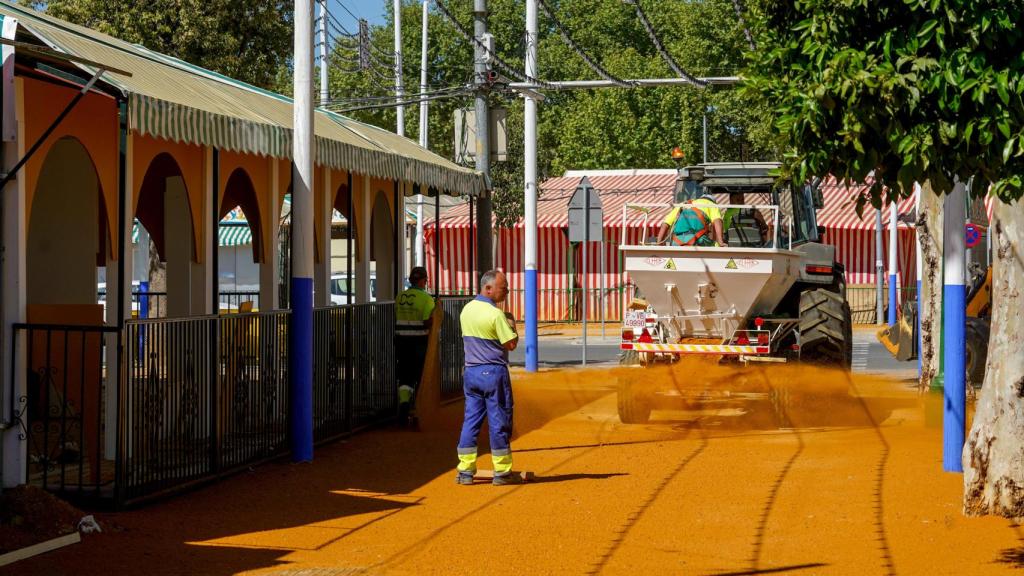 Trabajadores cubren las calles de albero en el recinto ferial.