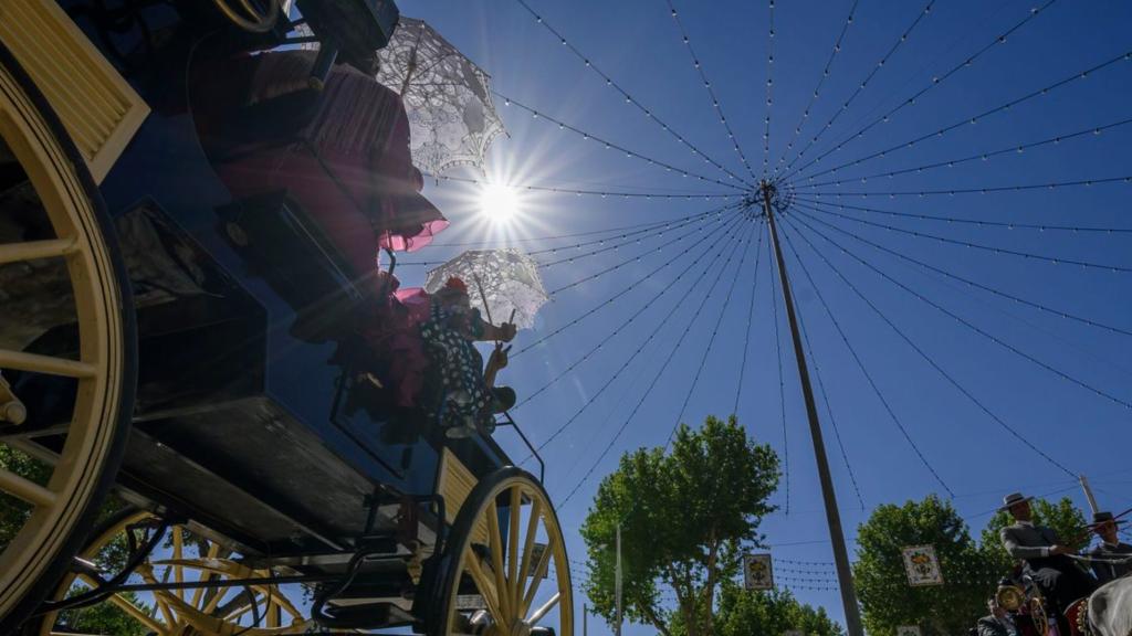 Un coche de caballos pasea por el Real de la Feria de Abril de Sevilla.